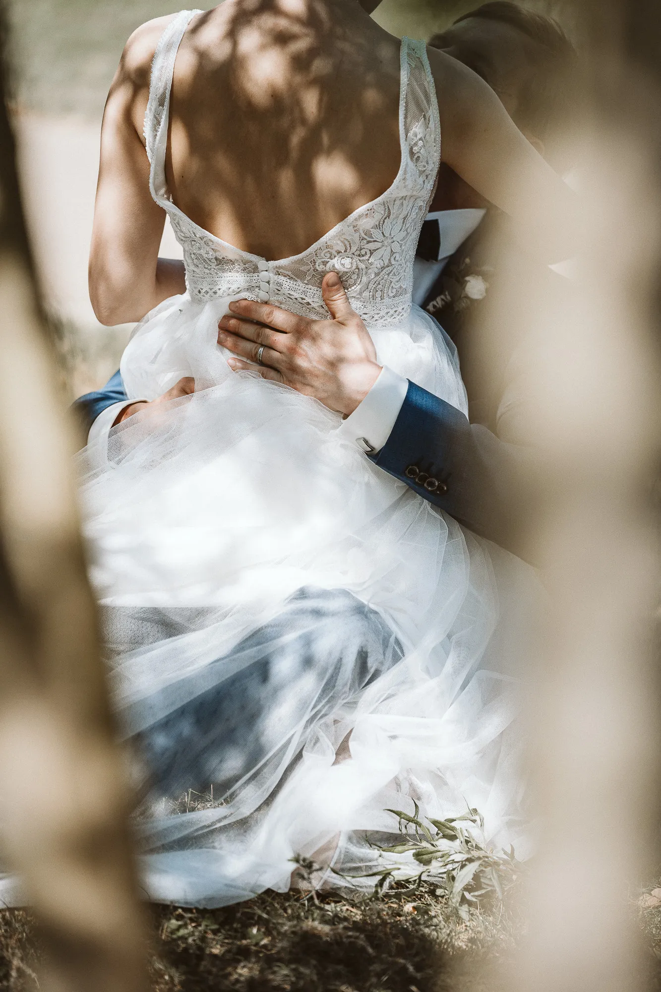 Hochzeitsfotograf Potsdam Das Brautpaar sitzt zusammen und man sieht vom Bräutigam die Hände auf ihr rücken