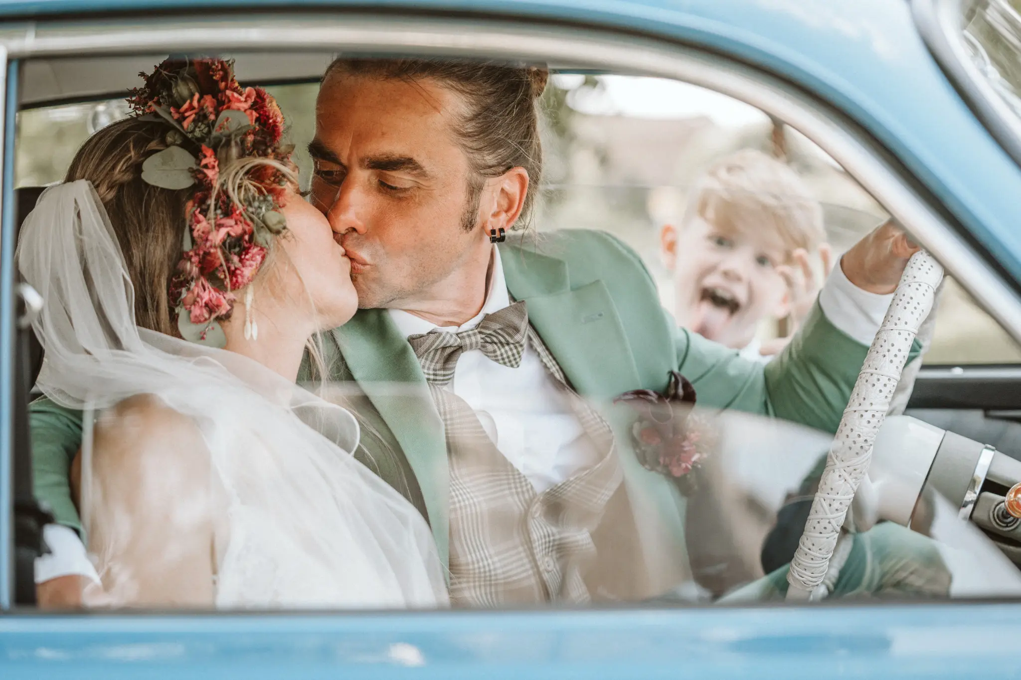 Hochzeitsfotograf Potsdam Brautpaar im Auto und kind macht faxxen im hintergrund
